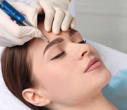 Young woman during procedure of permanent eyebrow makeup in beauty salon, closeup